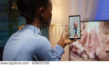 African Famele Having Conference Call With Her Doctor About Illness Treatment Sitting In Living Room