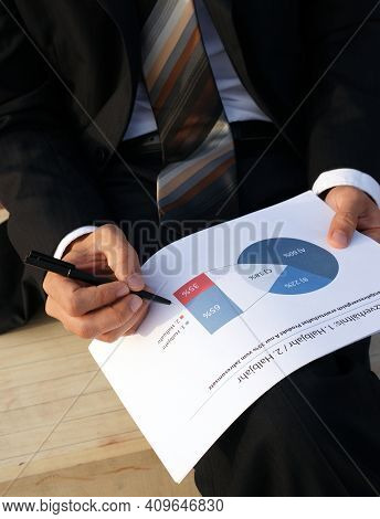 Businessman Evaluates Company Data And Checks Charts And Values