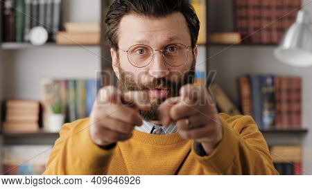 Man Points His Finger To You. Serious Frowning Bearded Man With Glasses In Office Or Apartment Room 