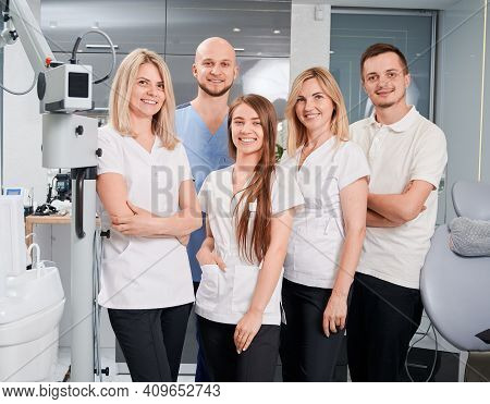 Dentists Looking At Camera And Smiling While Posing In Modern Dental Office. Women Expressing Positi