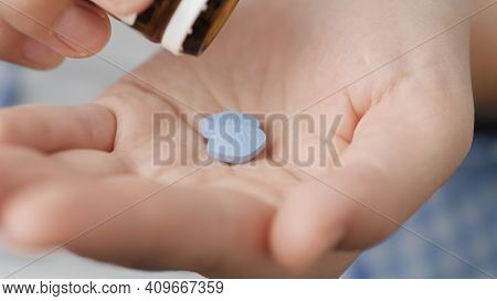 Two Big Blue Diamond-shaped Pills Labeled 100 Fall Into Palm Of Hand From Pill Bottle. Close-up, Fro