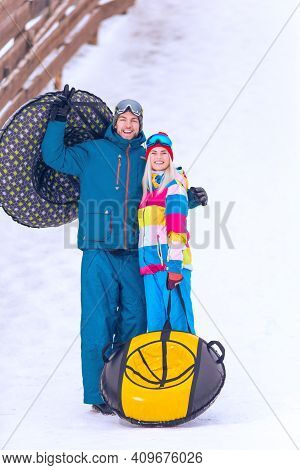 Portrait Of Lovely Caucasian Couple Having Tube Activities In Winter Time On Skiing Resort In Mounta