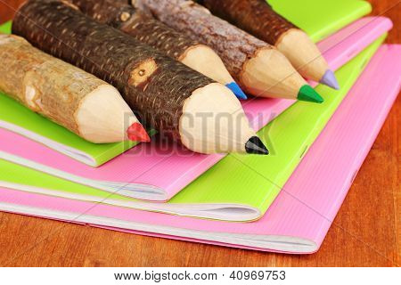 Kolorowe kredki drewniane z exercisebooks na drewnianym stole