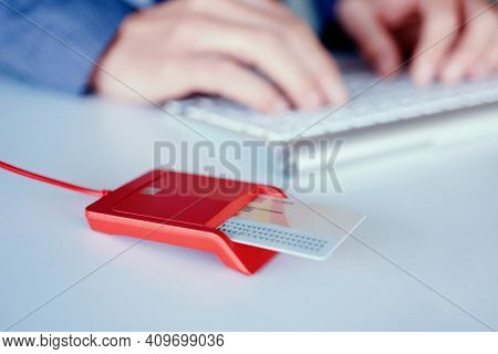 closeup of an electronic identification in a red reader on a front desk, and a young caucasian man, wearing an elegant blue suit sitting at the desk