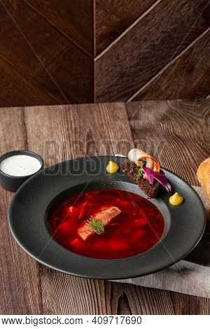 Ukrainian Traditional Borshch. Beetroot And Cabbage Soup With Meat. Close-up Of The Dish In Black Pl
