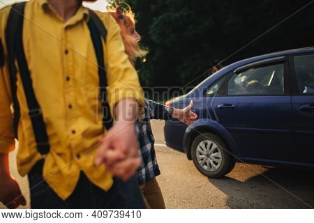 A Man And A Woman Are Hitchhiking. A Young Couple Goes Hitchhiking Around The Country. Free Hitchhik