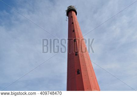 A Tall Red Lighthouse Reaching For The Sky At Atlantikwall, Netherlands