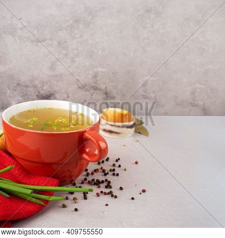 Hot Homemade Beef Bone Broth With Collagen And Amino Acids In Red Bowl With Red Napkin And Green Oni
