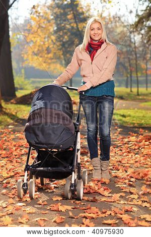 Young mother taking a walk in the park with her baby in a pushchair