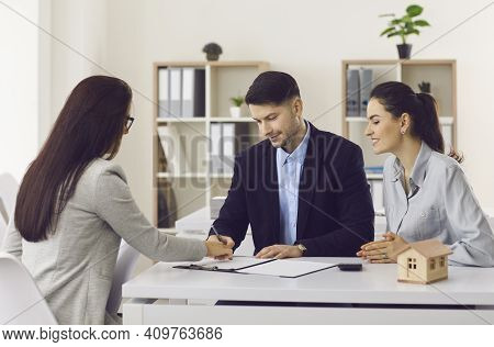 Happy Couple Signing Contract Of Buying New Apartment In Office
