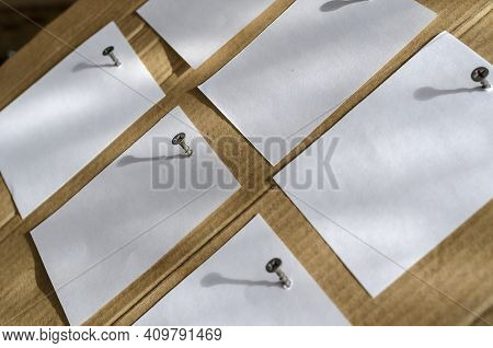 Six Note Paper Stickers Are Screwed To The Brown Cardboard With Metal Screws. White Blank Square She