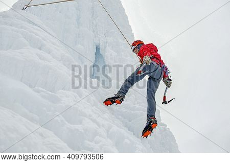 Alpinist Woman With Ice Tools Axe In Orange Helmet Climbing A L