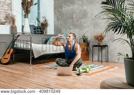 The Young Woman Goes In For Sports At Home. Cheerful Sportswoman With Black Hair Grinking Water On T