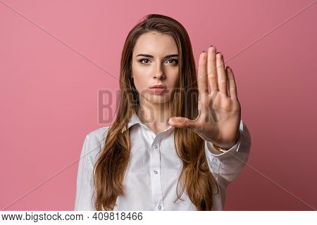Keep Away And Leave Me Alone. Serious Brunette Girl Keeps Palm Forward At Camera, Makes Forbid Sign,