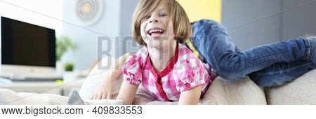 Girl And Boy Play Around On Couch At Home And Laugh. Baby Play And Pampering Concept