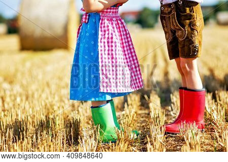 Two Kids In Traditional Bavarian Costumes And Red And Green Rubb