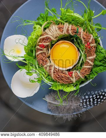 Egg In A Nest With Herbs And Broken Eggshell