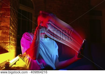 Cinematic Portrait Of Stylish Woman In Neon Lighted Interior Using A Smartphone. The Face Is Smeared
