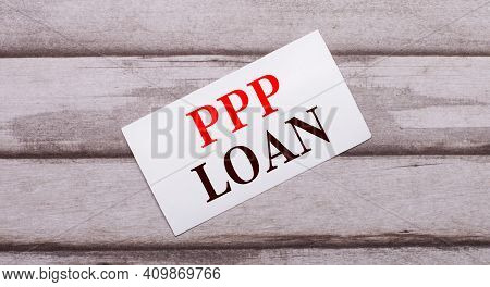On A Wooden Background, There Is A White Card With Red Text Ppp Loan