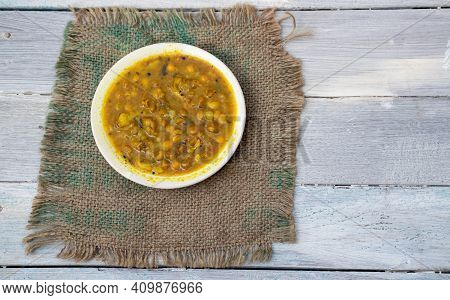 Ghugni Curry Or Curried Yellow Peas In A Plate On Burlap Fabric Isolated On White Wooden Background 