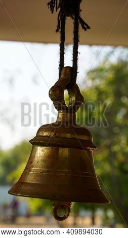 Bronze Bell In Indian Temple In The Green Crops Blur Background. Hindu Temple Brass Bell Hanging In 