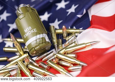 M18 Smoke Grenade And Many Yellow Bullets And Cartridges On United States Flag. Concept Of Gun Traff