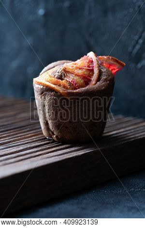Brownie Muffin With Blood Orange Slices On Ribbed Oak Cutboard On Dark Plaster Background Front View