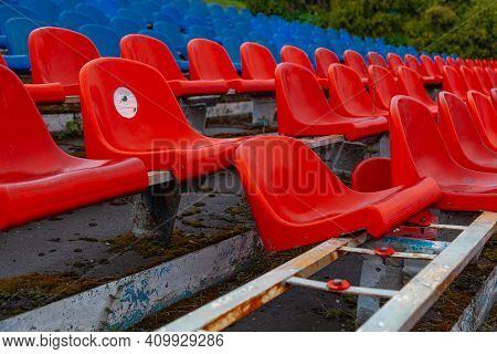 Several Rows Of Plastic Chairs In An Old Stadium. Some Of The Chairs Are Broken