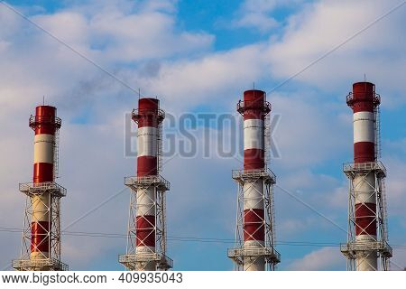 Four Red And White Striped Chimneys Against A Cloudy Sky
