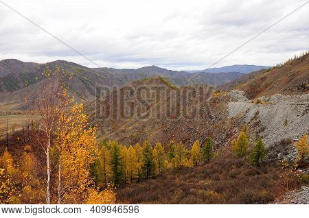 A Look Through Yellowed Birches To A Rocky Cliff Overlooking A Picturesque Autumn Valley.