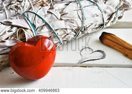 A Close Up Image Of White Sage And Holly Wood Smudge Sticks Next To A Heart Shaped Drawing.