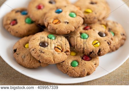 Cookies With Colorful M&ms Chocolates Close-up On A White Ceramic Plate. Low Depth Of Field, Blurred
