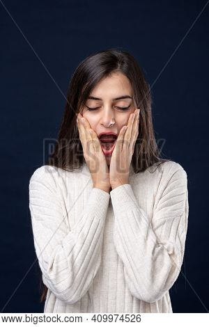 Attractive Young Woman With Eyes Closed, Mouth Open And Hands To Her Cheeks Conceptual Of Yawning In