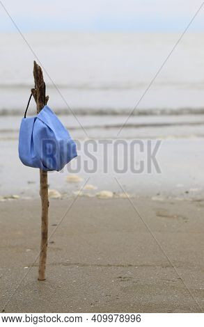Surgical Mask Hanging From The Branch On The Shore Like A Flag Flying