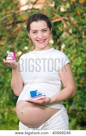 Holding egy sarok nélküli Női papucsok, baba, különböző színekben, a parkban szabadtéri terhes nő
