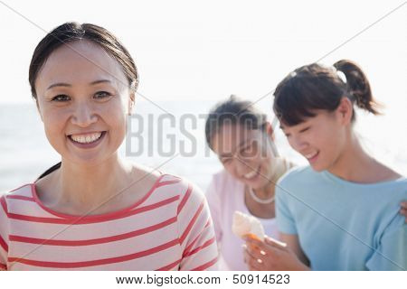 Portrait of multi- generational family on the beach, looking at Shell