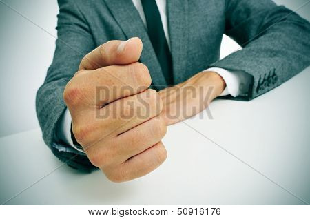 man wearing a suit banging his fist on the desk