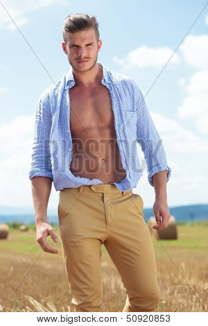 young casual man posing outdoor with opened shirt, looking into the camera