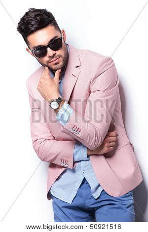 young casual man acting thoughtful while holding his hand on his chin while looking down. on white background
