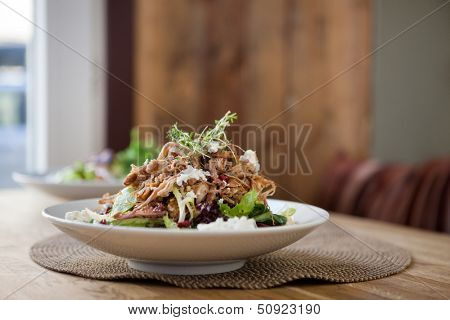 Closeup of tasty chicken salad on plate at table