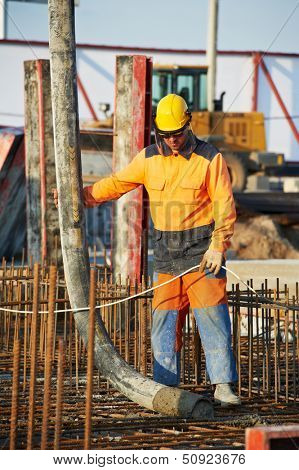 builder worker standing near trailer-mounted boom concrete pump on metal rods reinforcement of concrete casting formwork