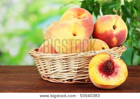 Ripe sweet peaches in wicker basket, on bright background