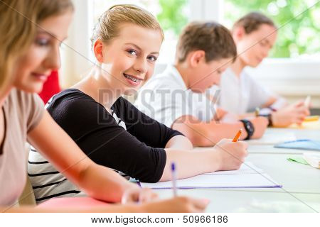 Students or pupils of school class writing an exam test in classroom concentrating on their work