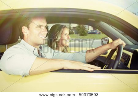 Two young smiling people in a yellow car