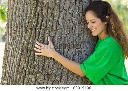 Smiling female environmentalist hugging tree trunk in park