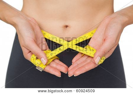 Close-up mid section of a woman measuring waist over white background