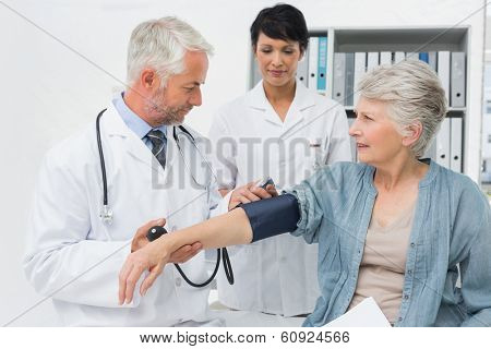 Male doctor measuring blood pressure of a senior patient in the medical office