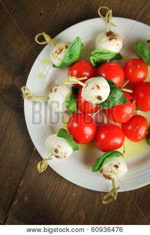 Top view of delicious skewer with bocconcini, cherry tomatoes and basil or caprese