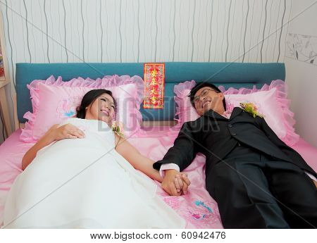 Bride And Groom Hold Their Hand And Lay On The Bed As Chinese Traditional