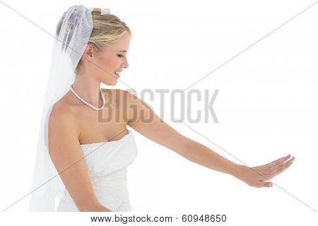Beautiful bride in off shoulder dress looking at wedding ring over white background